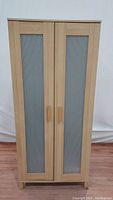 Front view of Ikea Aneboda wardrobe showing two frosted pin-striped glass panels in light wood veneer frame and wooden handles.