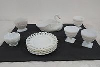 Top-down view of all items showing the swan candy dish center, lace-edged plates, bowls with fruit motifs, and sherbert bowls