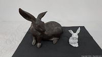 Photo of both rabbit statues side by side showing size difference and details
