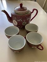 Photo of the tea set including teapot and four cups displayed on table.