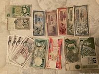 Photo showing a variety of banknotes from different countries including British, Italian, Thai, and others arranged on a surface.