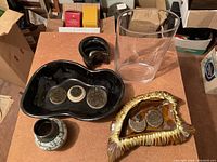 Overview: two ceramic containers, glass cylinder, patterned bud vase and metal pin holders arranged on table.