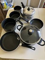 Overview of all cookware including black pots, pans, and stainless steel double broil pot.