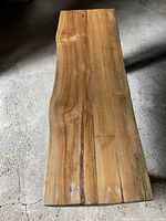 Top view of teak bench seat showing smooth, polished natural wood with visible grain and color variations.