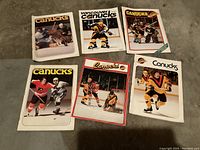 Photo showing all six Vancouver Canucks hockey programs with various action shots and player images on the covers.