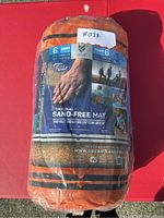 Original sealed packaging of CGEAR Sand-Free Mat in orange color, showing branding and product benefits.