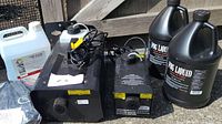 Two fog machines placed side by side on ground with power cords and fluid bottles behind.