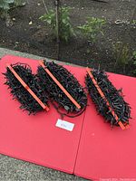 Three bundles of Halloween string lights, tightly coiled and secured with orange straps, primarily orange and purple bulbs on black wires, placed on a red surface outdoors