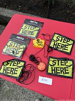 Five Halloween footpad activators labeled STEP HERE with wires, two activation buttons (one orange, one yellow with skull) on a red surface outdoors.