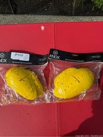Two yellow Knox motorcycle protective pads in sealed packaging sitting on a red surface, one labeled with #045