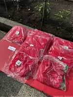 Multiple stacks of red Hanes T-shirts individually packaged in plastic, sizes visible through packaging and labels.