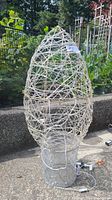 Large outdoor Christmas candle-shaped LED decoration with white woven string lights and mesh candle base.
