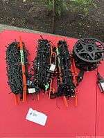 Multiple bundles of purple LED light strands coiled on orange plastic reels with power adapters shown on red table.