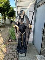 Full frontal view of the lunging reaper animatronic outdoors showing tall hooded skeletal figure with tattered black and brown robe and scythe.