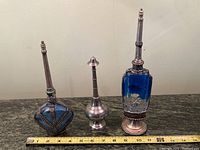 Photo of all 3 vintage perfume bottles together with measuring tape for scale.