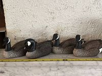 Four Canada Goose bird decoys displayed side by side on a marble surface showing detailed feather paint and wear.