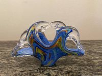 Front view showing blue marbled art glass with clear curved edges and orange and green color accents