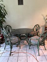 Full view of the patio set showing all four rattan chairs around glass-top table.