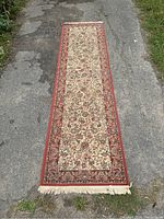 Full view of the vintage Eaton runner rug on pavement showing full length and fringe.