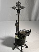 Full view of the antique silverplate basket showing the five feet, vertical rod, cherub figure, and ornate top decoration