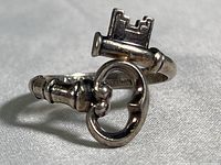 Close-up front angle of silver ring shaped like a skeleton key with detailed ridges and key teeth visible.