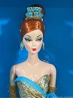 Close-up of Barbie doll's face showing hair styled in a formal updo with happy new year headpiece and detailed makeup.