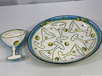 Photo showing the large oval platter and the matching martini glass-shaped dish, both with colorful cocktail-themed hand painted designs.