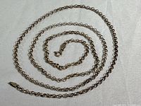 Full view of a vintage Italian sterling silver chain laid out coiled on a white surface, showing the chain style and length.