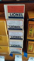 Stack of Lionel boxes labeled with model numbers and rail lines including B&O 9130 hopper and Boston & Maine 6464-475
