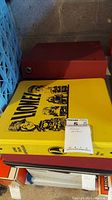 Photo showing yellow Lionel branded binder on top of a red binder, with attached auction tag.
