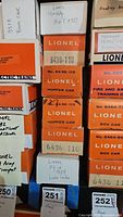 Stacked Lionel model train car boxes including multiple hopper car boxes and other boxed cars