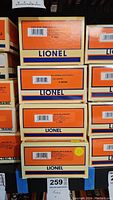 Stack of Lionel train car boxes showing labels with item names and numbers: Executive Inspection Car - Blue 18454, Baltimore and Ohio Gondola 26042, IND Boxcar 6464, Seaboard Boxcar 29285, Seaboard Waffle Sided Boxcar 15014.