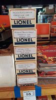 Stack of 5 Lionel train car boxes with model names and numbers visible on each box. Labels handwritten on white tape.