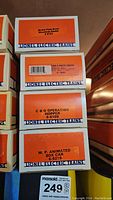 Stacked boxes showing labels of four Lionel Electric Trains: Nickel Plate Road Woodside Reefer 6-5722, Texas & Pacific Reefer 6-18131, C & O Operating Hopper 6-6109, M. P. Animated Box Car 6-9219