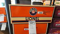 Two stacked Lionel orange and cream boxes with MaxSold lot tag visible