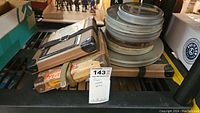 Photo of metal film reels stacked on a wooden box packed on a shelf.