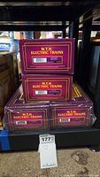 Four MTH Electric Trains boxes stacked on shelf, each labeled with model numbers and logos for New Haven and Jersey Central lines.
