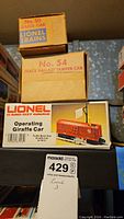 Boxes of Lionel No. 50 Gang Car, No. 54 Track Ballast Tamper Car, and Operating Giraffe Car 7913 arranged stacked showing branding and model numbers.