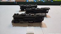 Three black Lionel steam locomotive engines displayed front to back on table