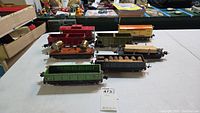 Top down view of seven Lionel Lines tinplate train cars including a caboose on table.