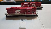 Two Lionel Central Railroad New Jersey diesel locomotives, red and white, model numbers 8550 and 8561 shown on display table.