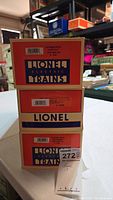 Stack of three Lionel Electric Train boxes showing product labels and barcodes for each car in the lot. The labels confirm the exact Lionel model numbers and names.