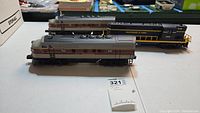 Two Lionel model electric trains, front and side view, showing Erie Lackawanna 242 in silver and maroon, and Baltimore & Ohio 8662 in blue and yellow paint.
