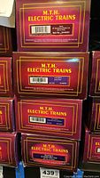 Boxes of four MTH Electric Train models showing product details and item numbers.