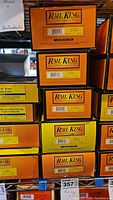 Stacked yellow boxes of Rail King branded model train cars, showing box labels and brand.