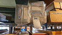 Three Williams Electric Trains branded boxes with window displays, stacked on metal shelf, showing original packaging of Amtrak passenger cars.