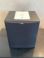 Front view of subwoofer with owner’s manual on top