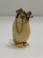 Front three-quarter view showing carved bone feathers, gold-tone spectacles and chain drape