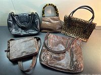 Five leather handbags arranged against white background