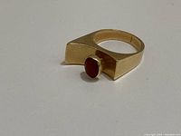Angled view showing the bevelled top mounting and oval red carnelian cabochon